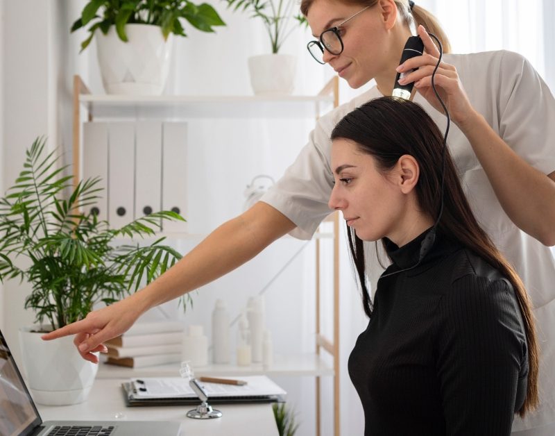 Salon professional performing hair consultation while reviewing results on digital salon software.